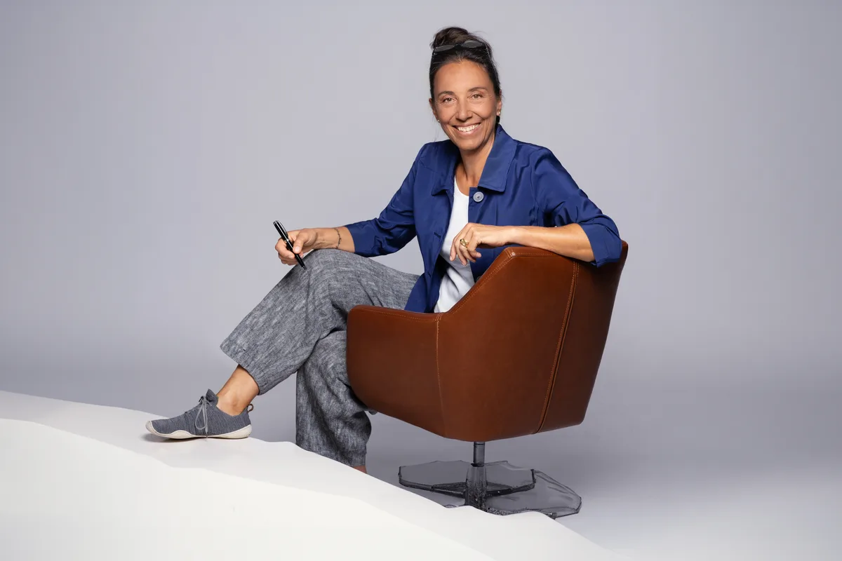 Auf dem Bild zu sehen ist Claudia Knecht auf einem Sessel sitzend
